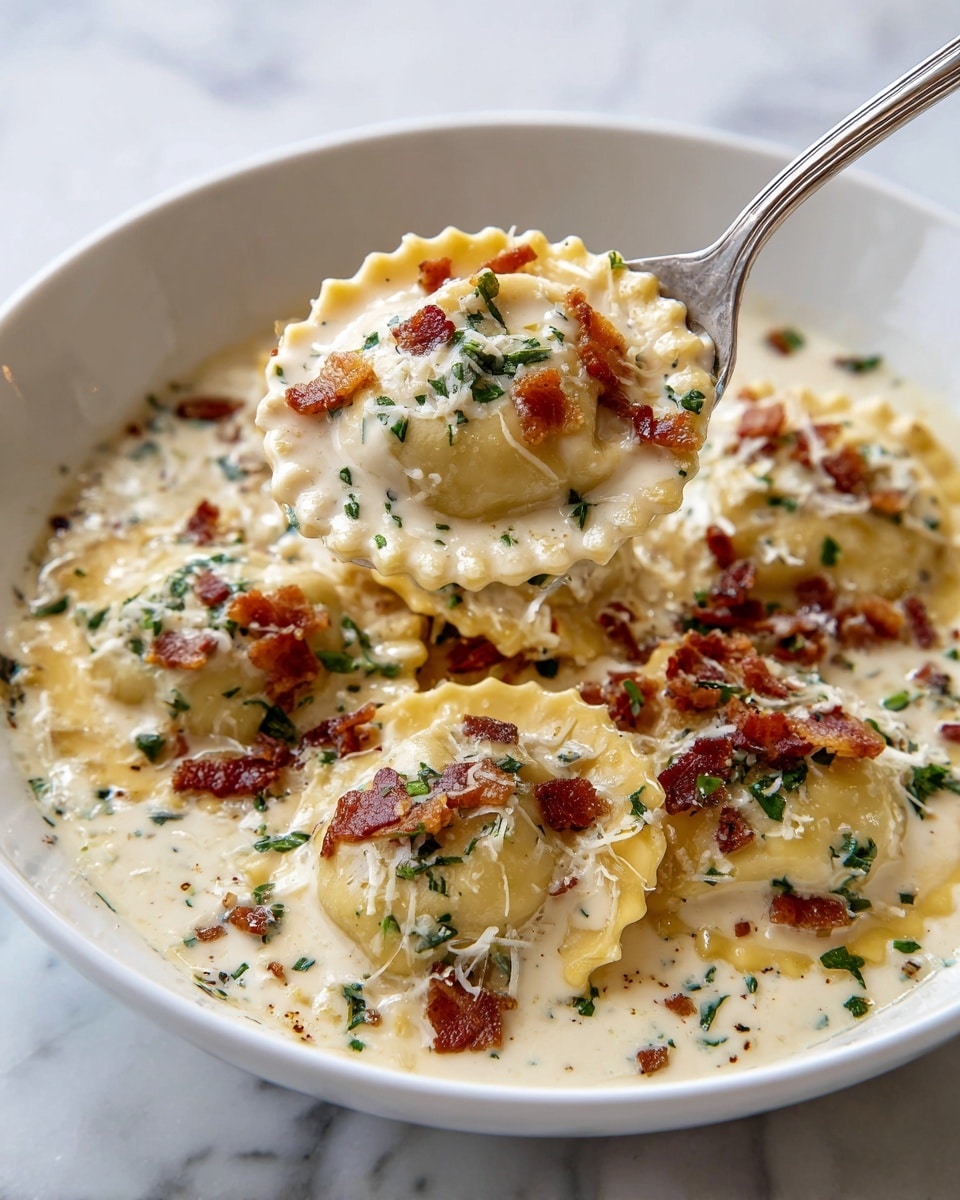 A white bowl filled with several pieces of round ravioli pasta coated in a creamy white sauce. The ravioli have a slightly yellow tint with ruffled edges, and the sauce is smooth and rich. On top, there are small brown crispy bacon bits scattered evenly along with finely chopped fresh green herbs. Grated cheese is sprinkled across the ravioli, melting slightly into the sauce. A silver spoon is lifting a ravioli piece, showing the creamy sauce coating and garnishes in close-up. The setting is on a white marbled surface. photo taken with an iphone --ar 4:5 --v 7
