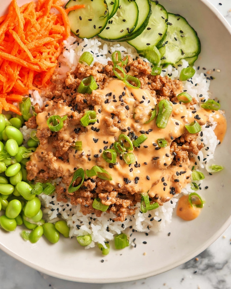 A white plate with a base layer of white rice sprinkled with black sesame seeds sits on a white marbled surface. On top of the rice, there is a generous layer of cooked ground meat covered with a light orange creamy sauce, garnished with green chopped scallions. To the side, there are bright green edamame beans and thinly sliced green cucumber pieces with some sauce drizzled on them. The top left corner shows some shredded orange carrots. Photo taken with an iphone --ar 4:5 --v 7