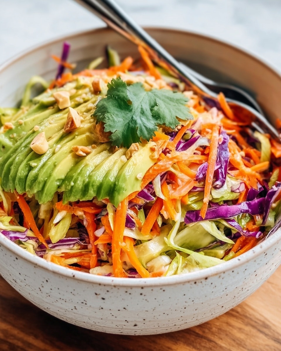 A white speckled bowl is filled with a colorful salad showing multiple layers. The base layer has thick, chunky slices of green avocado. On top of this, there is a mix of shredded bright orange carrots and thin purple cabbage strips, adding vibrant color and texture. There are bits of chopped nuts scattered over the salad, giving a crunchy look. A single green cilantro leaf sits near the center as decoration. Two silver forks are placed inside the bowl. The bowl is placed on a wooden surface seen at the edges but changed to a white marbled texture behind. Photo taken with an iphone --ar 4:5 --v 7