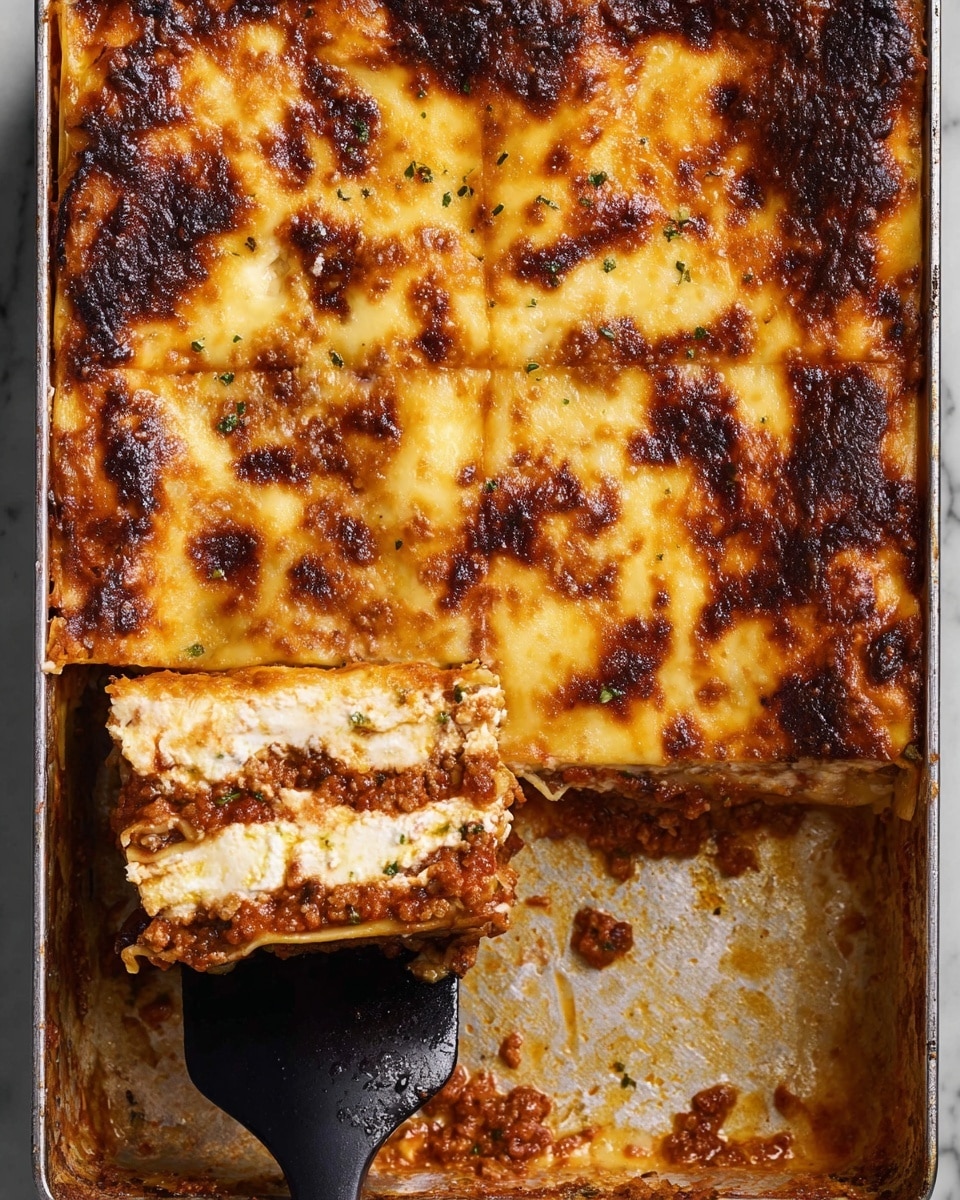 A close-up view of a baked lasagna in a rectangular silver pan sitting on a white marbled texture, with the top layer golden brown and bubbly, showing patches of dark brown crispy spots. One square piece has been cut and lifted slightly by a black spatula from the lower left corner, revealing four distinct layers inside: a browned top layer of melted cheese, a white creamy sauce layer beneath it, a thick red meat sauce layer with visible herbs, and a bottom pasta layer holding it all together. The edges of the pan show baked-on sauce and cheese residue. photo taken with an iphone --ar 4:5 --v 7