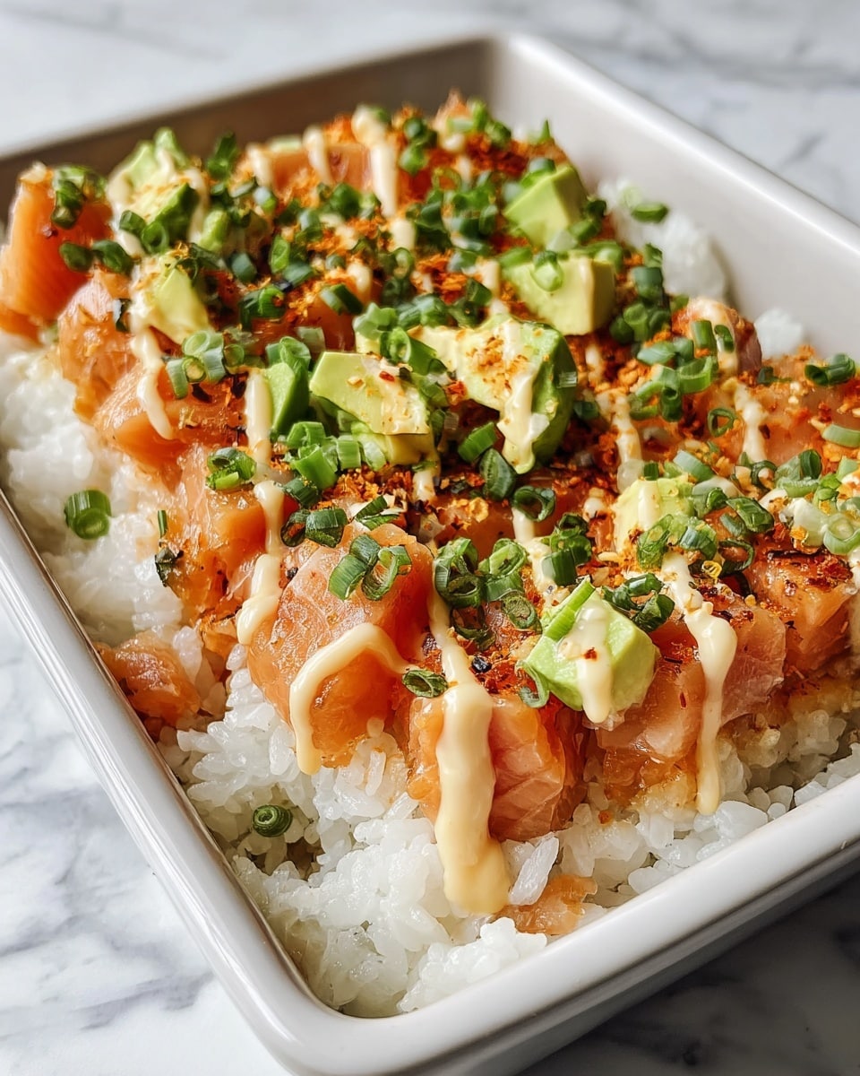 The dish is a sushi bake served in a white rectangular pan, showing two square layers. The bottom layer is white rice with a soft, sticky texture spread evenly. On top sits a thick layer of cooked salmon chunks, orange-pink with a slight glaze. The salmon is topped with a drizzle of creamy light beige sauce, scattered chopped green onions, and small pieces of fresh green avocado. The dish rests on a white marbled surface. photo taken with an iphone --ar 4:5 --v 7