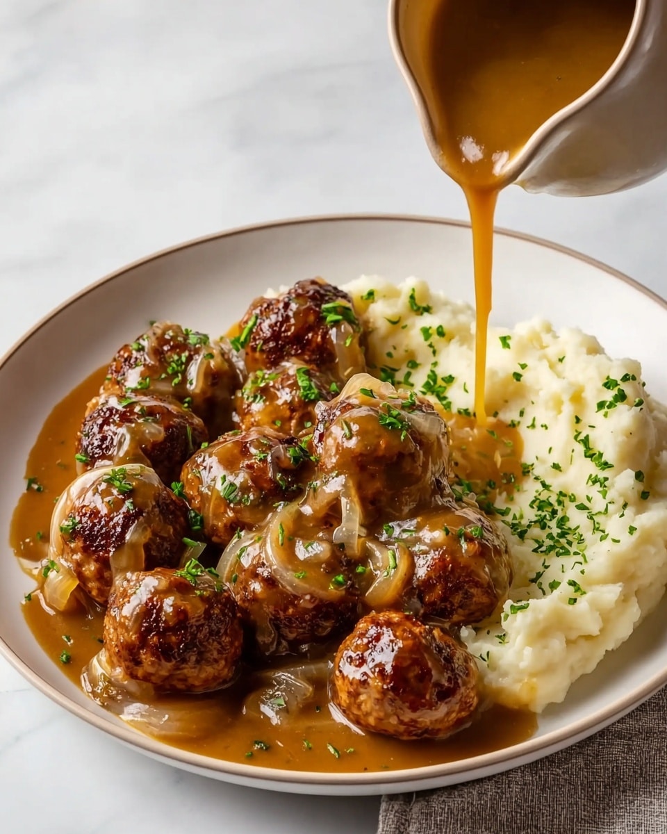 The dish shows a white round plate filled with two main layers: the bottom layer is creamy mashed potatoes on the right side, soft and white in color, sprinkled lightly with chopped green herbs; the top layer consists of about ten browned meatballs evenly spread across the plate, covered with a rich, brown sauce that contains visible cooked onion slices, drizzled from a beige gravy cup held above, with some sauce dripping down over the meatballs, all placed on a white marbled surface. Photo taken with an iphone --ar 4:5 --v 7
